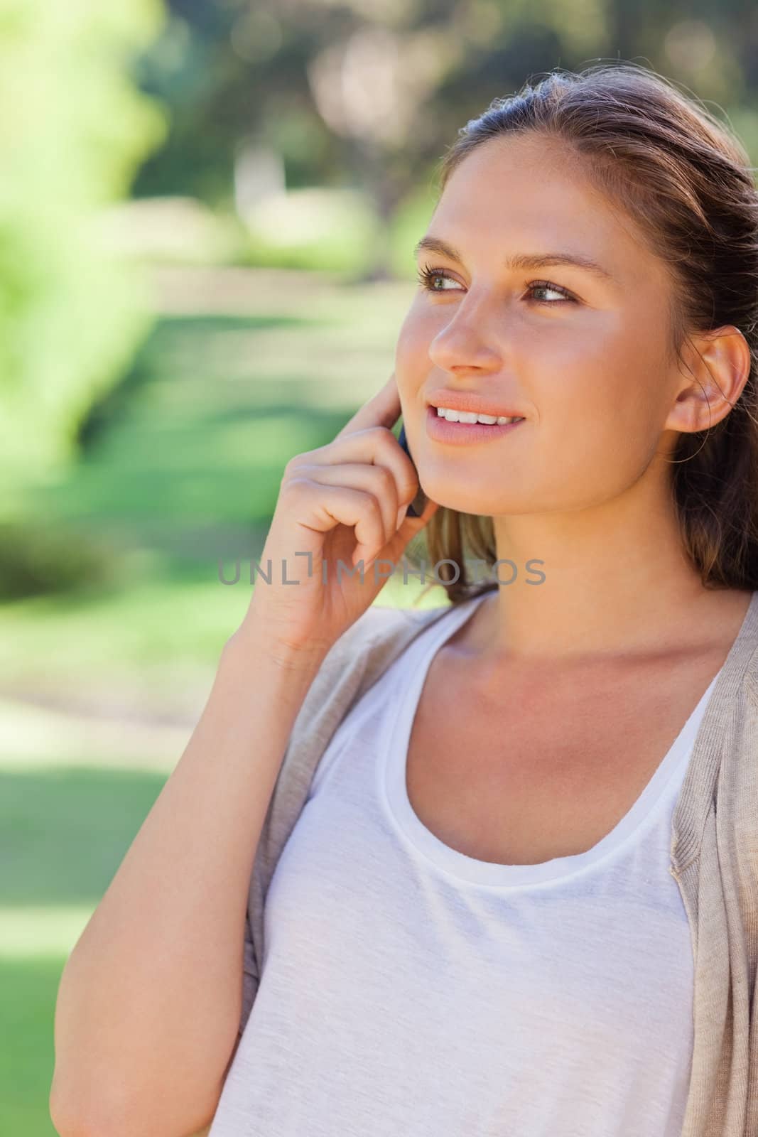 Smiling young woman on her mobile phone in the park