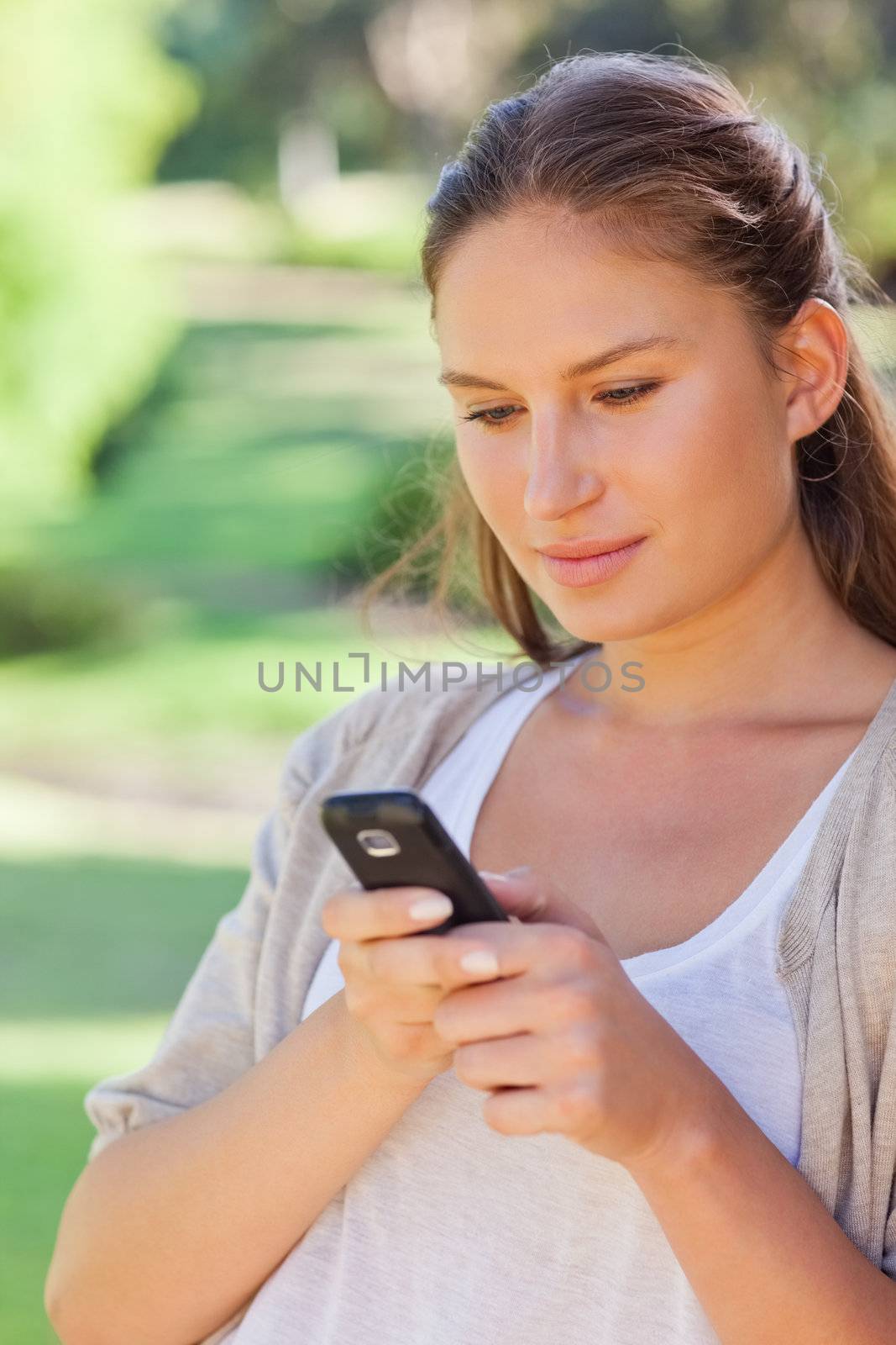 Close up of young woman writing a text message in the park