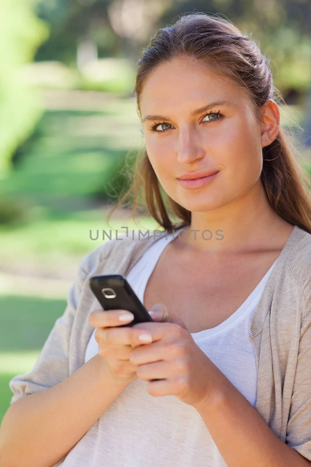 Close up of woman holding her cellphone in the park by Wavebreakmedia