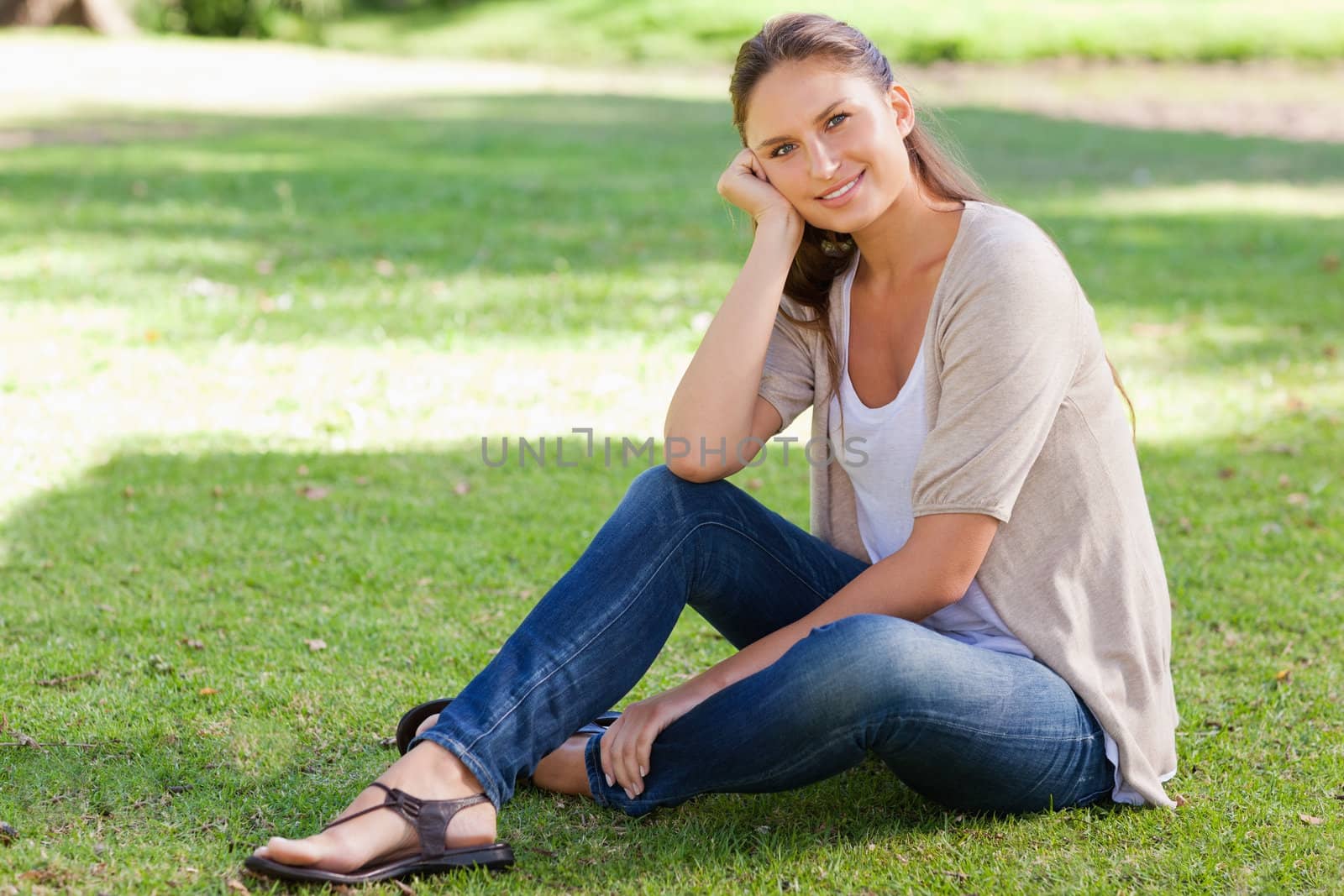 Smiling woman sitting on the grass by Wavebreakmedia