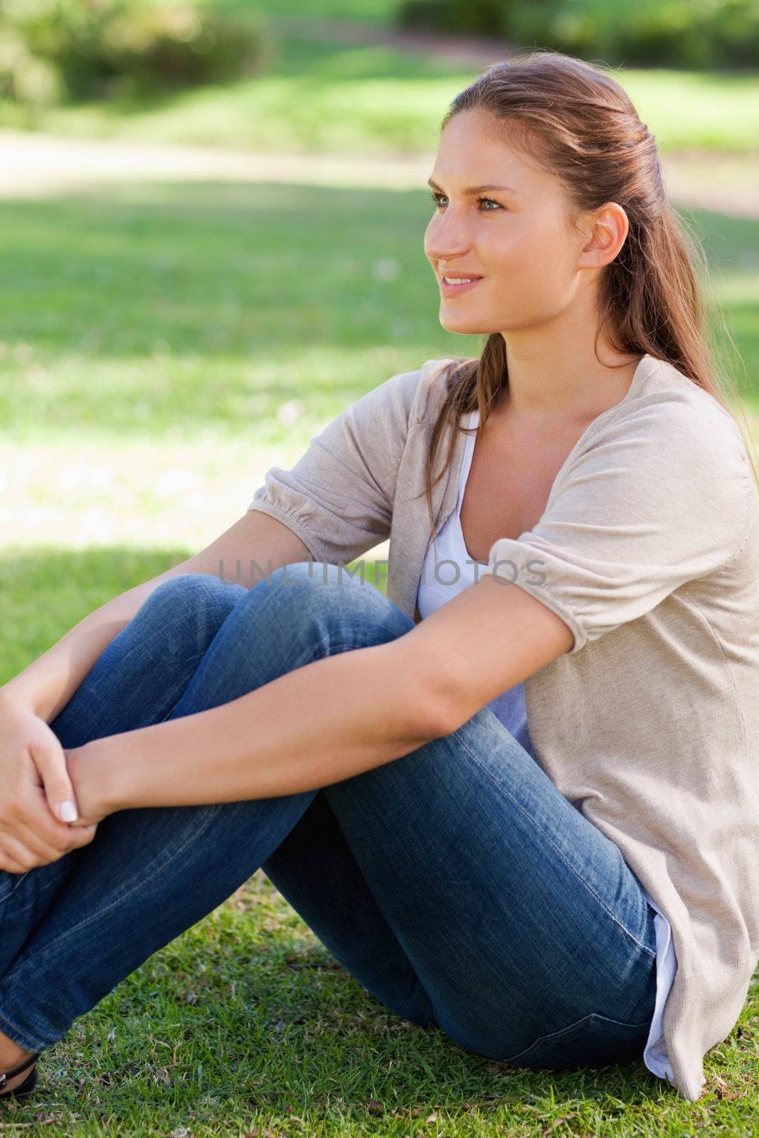 Side view of a young woman sitting on the lawn