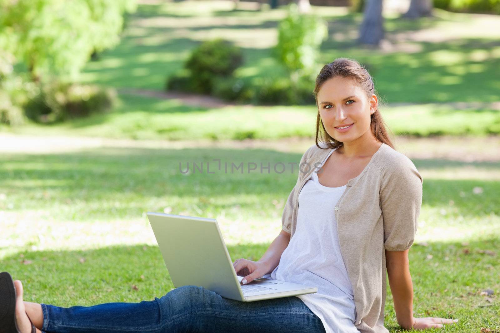 Woman with her laptop sitting on the lawn by Wavebreakmedia