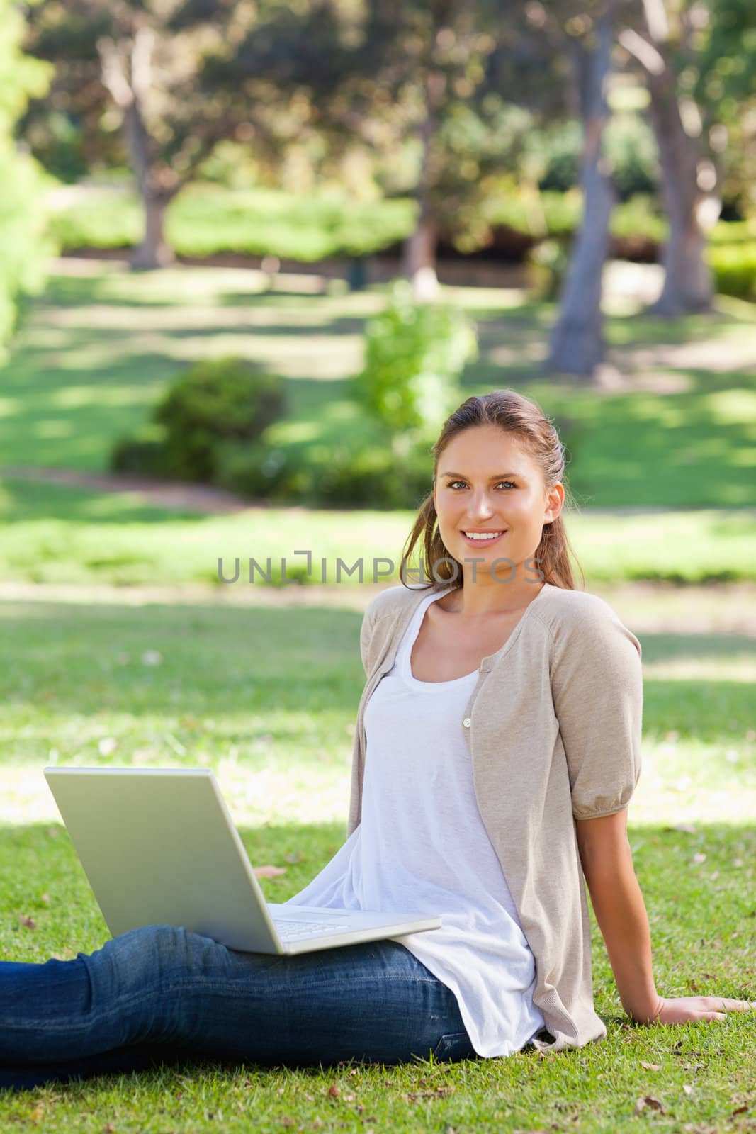 Smiling woman with her laptop sitting in the park by Wavebreakmedia