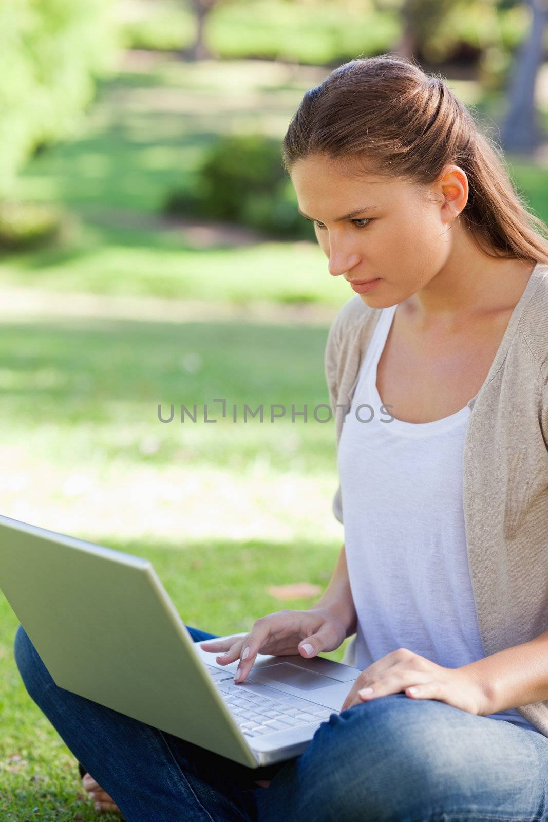 Young woman sitting on the lawn with her notebook
