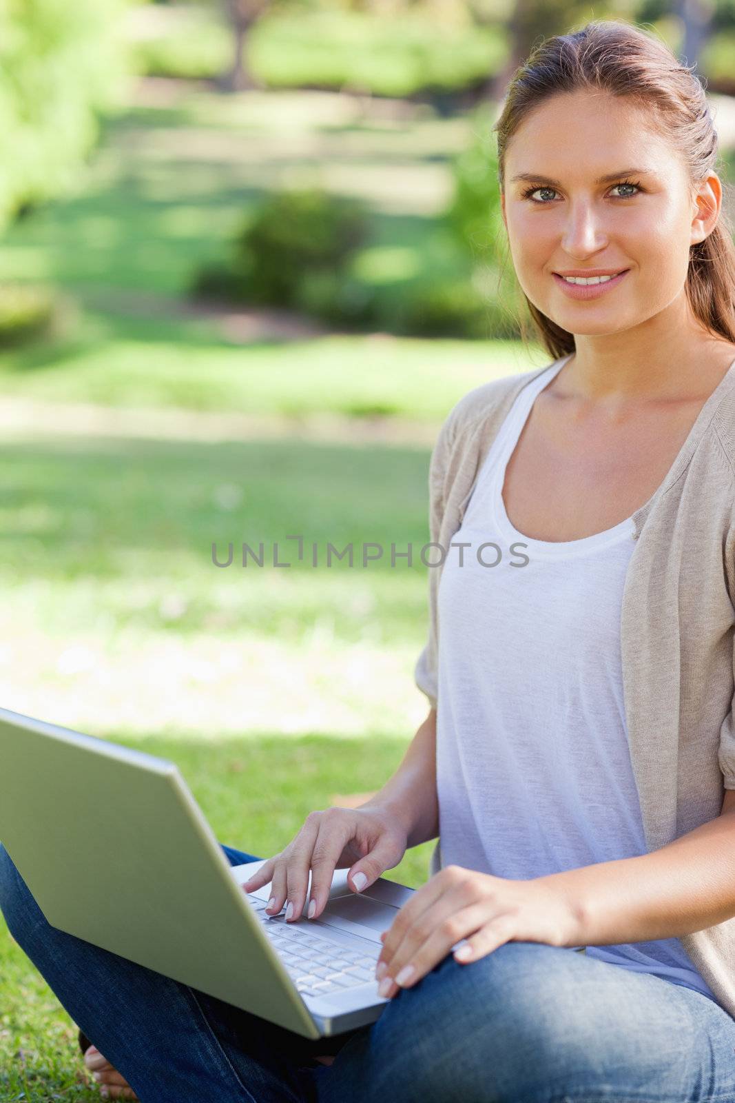 Smiling young woman working on her laptop in the park