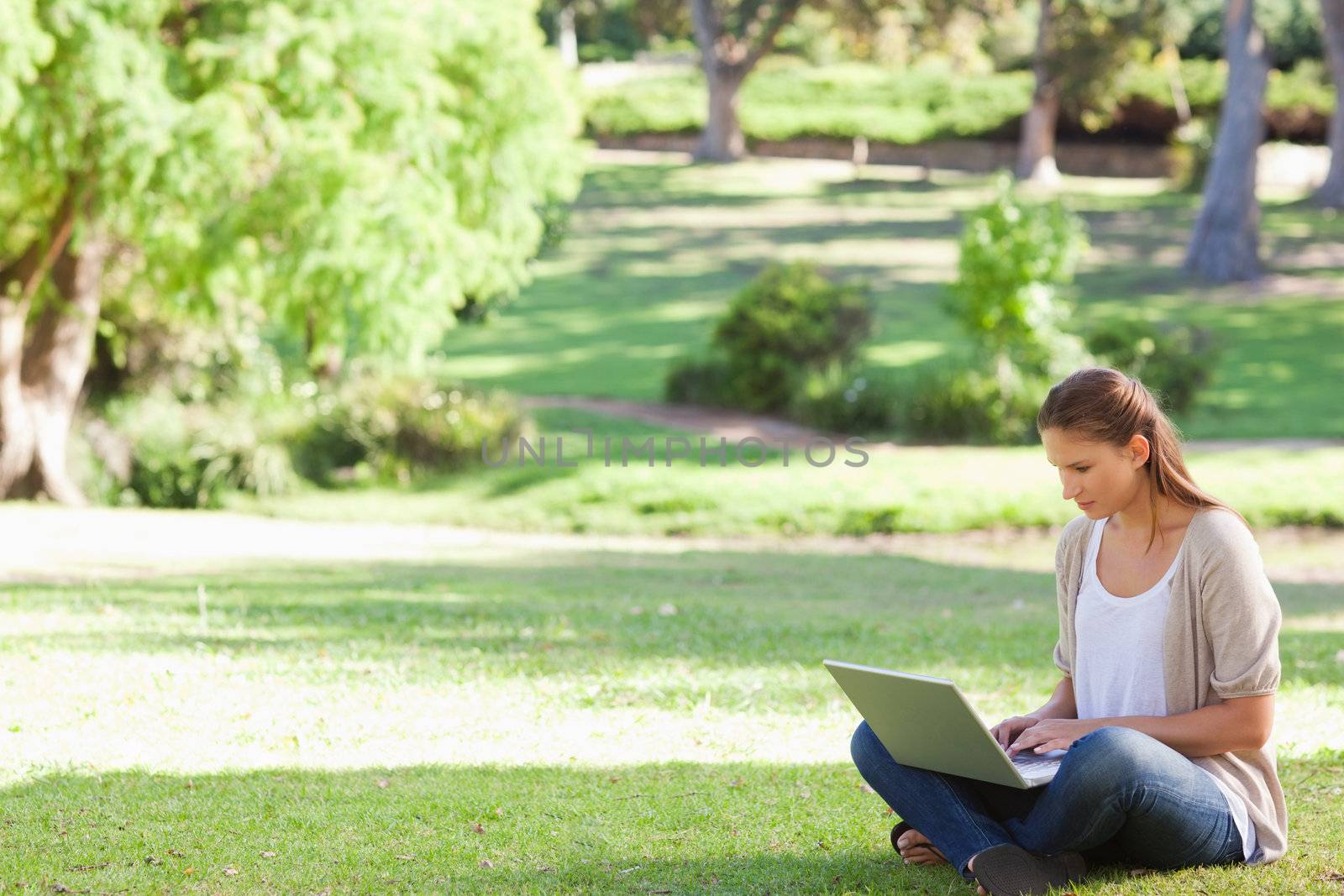 Young woman sitting on the lawn working on her notebook