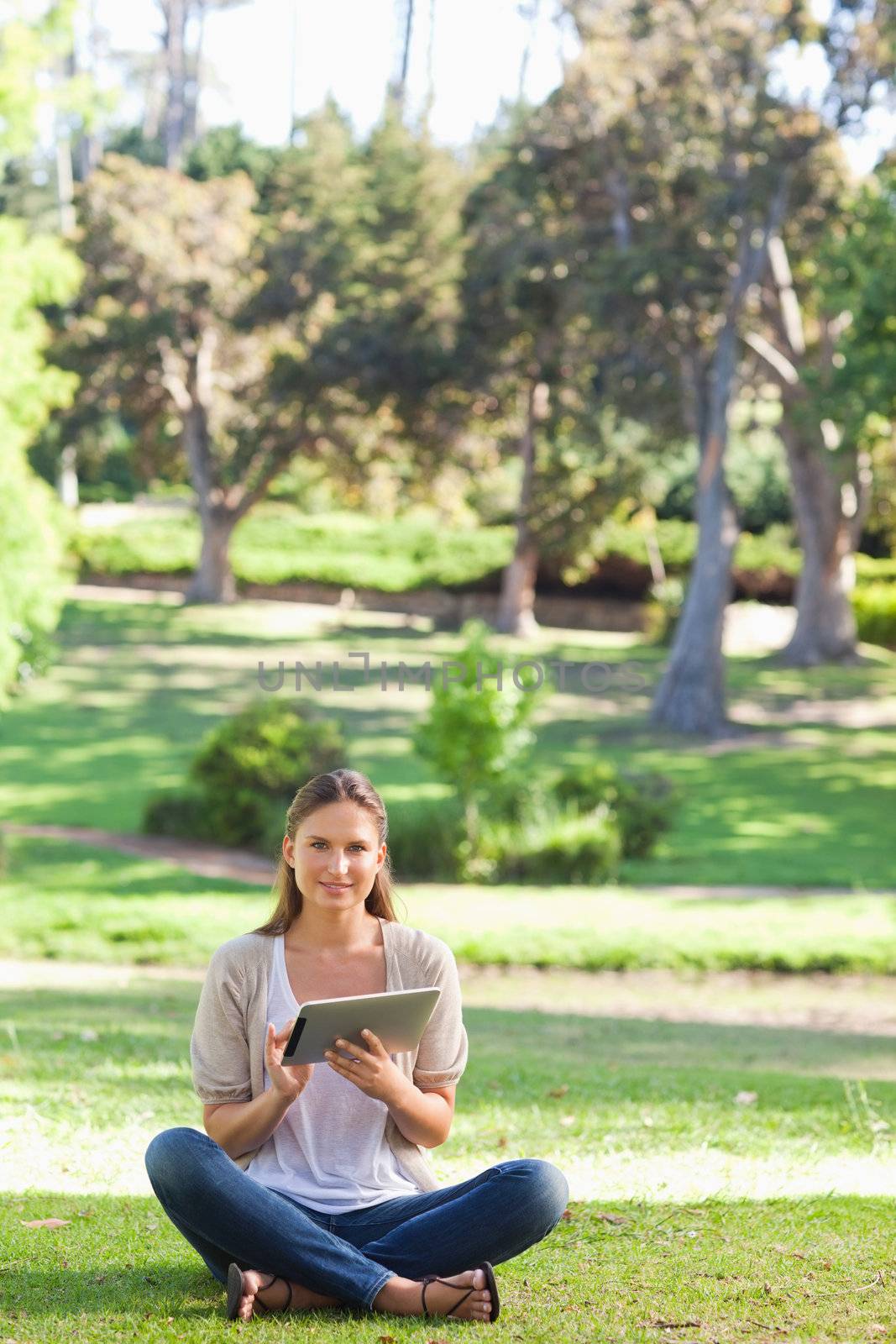 Woman sitting on the lawn while using her tablet by Wavebreakmedia