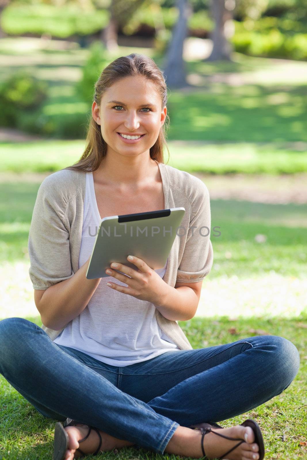 Smiling woman sitting on the lawn with her tablet computer by Wavebreakmedia