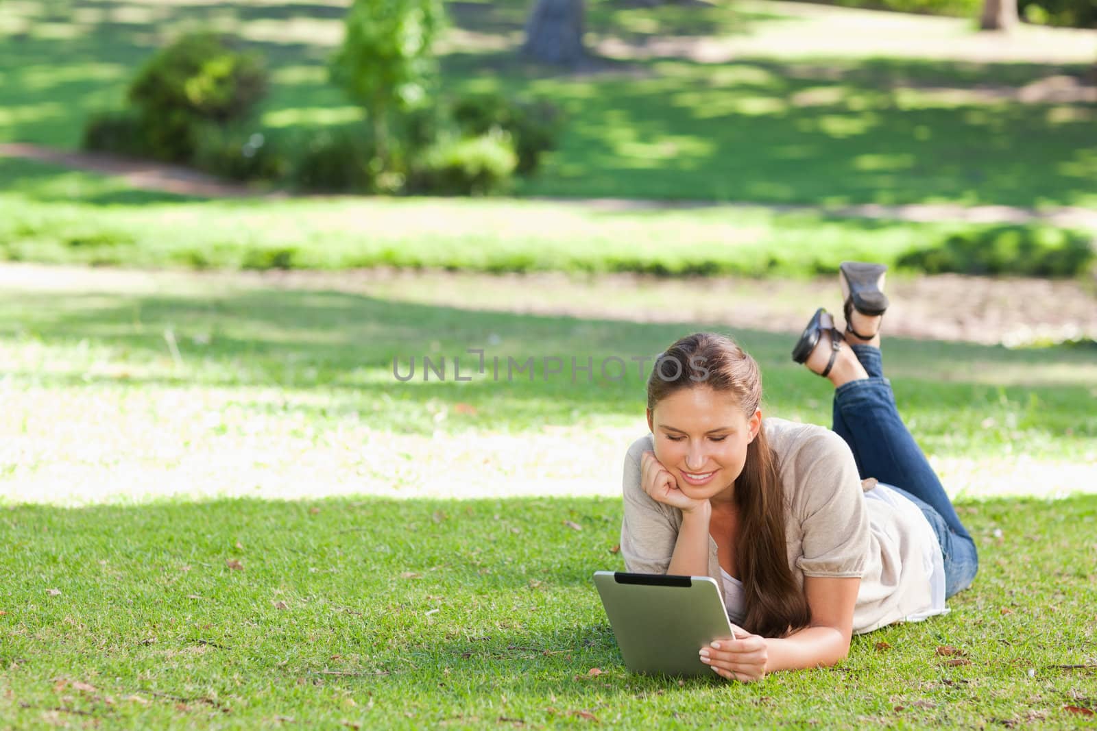 Young woman laying on the lawn with a tablet computer