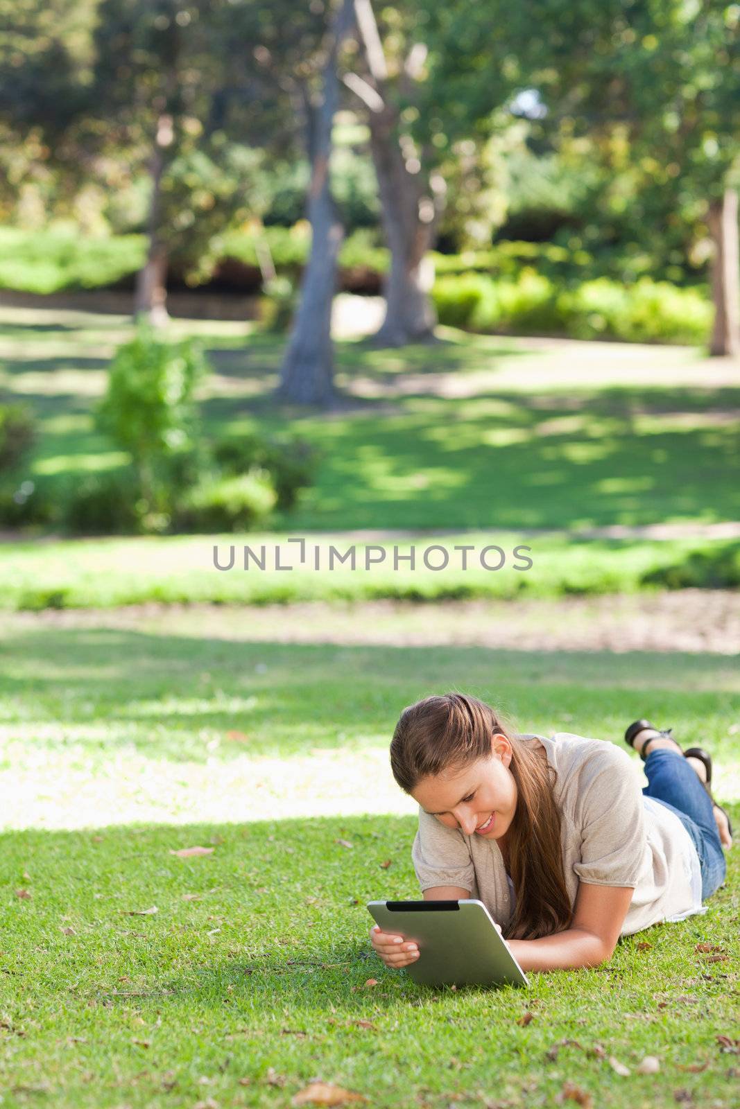 Young woman laying on the lawn using a tablet computer