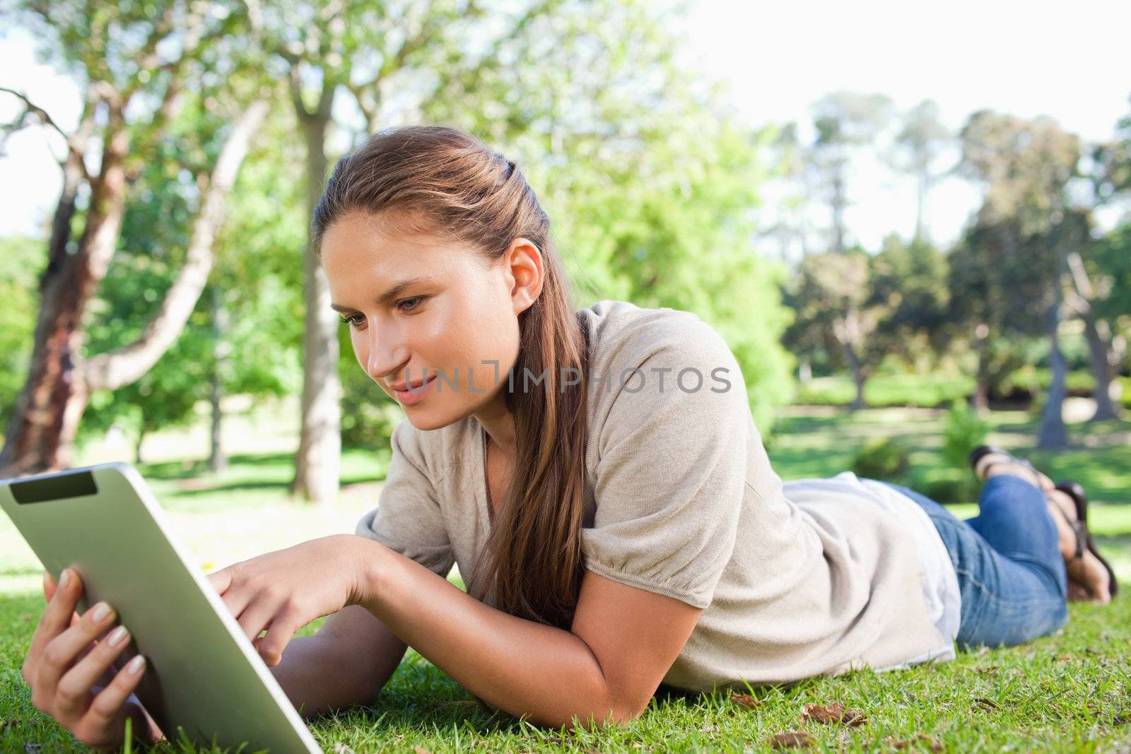 Woman with a tablet computer lying on the lawn by Wavebreakmedia
