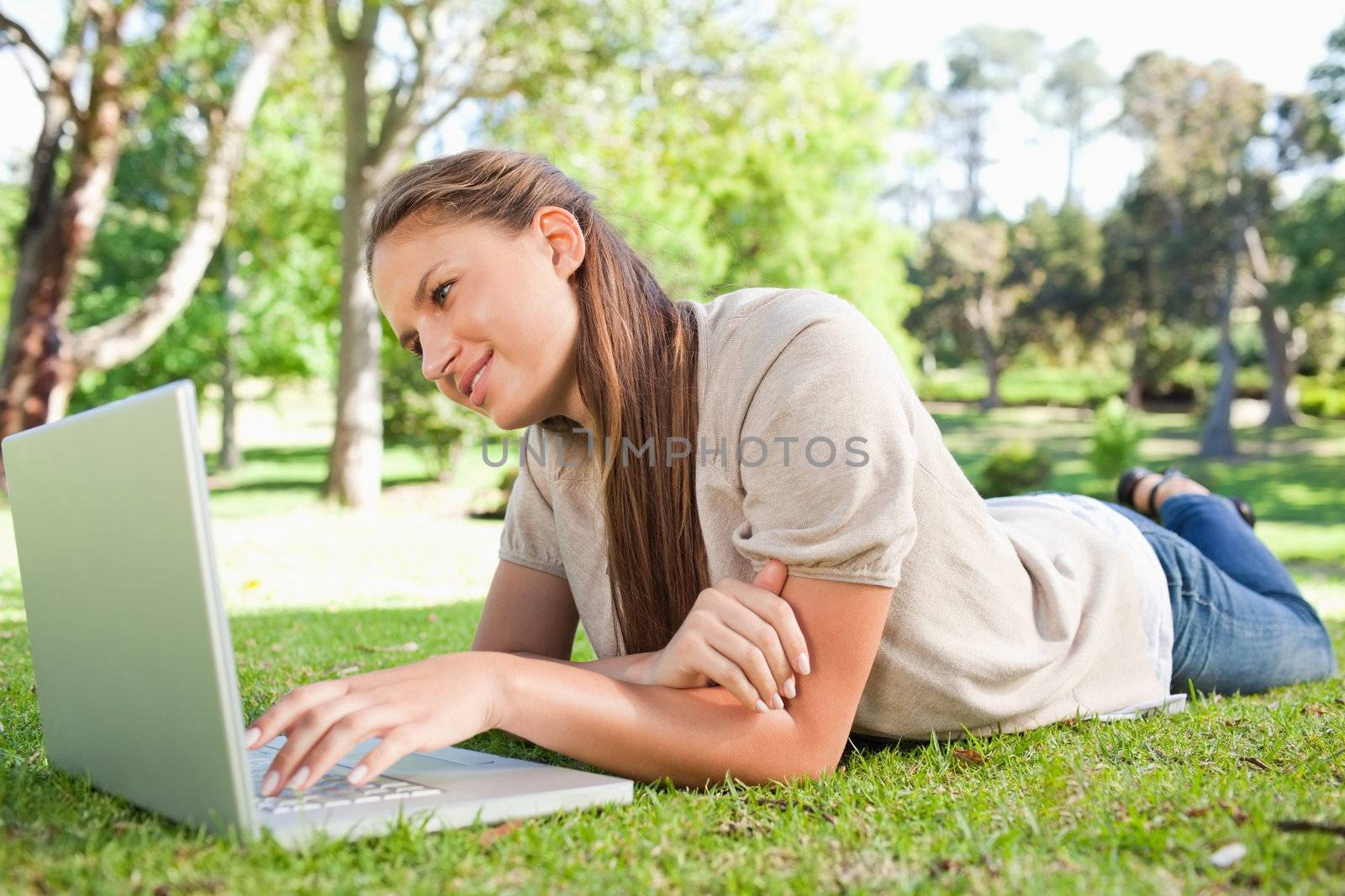 Woman lying on the lawn with her laptop by Wavebreakmedia
