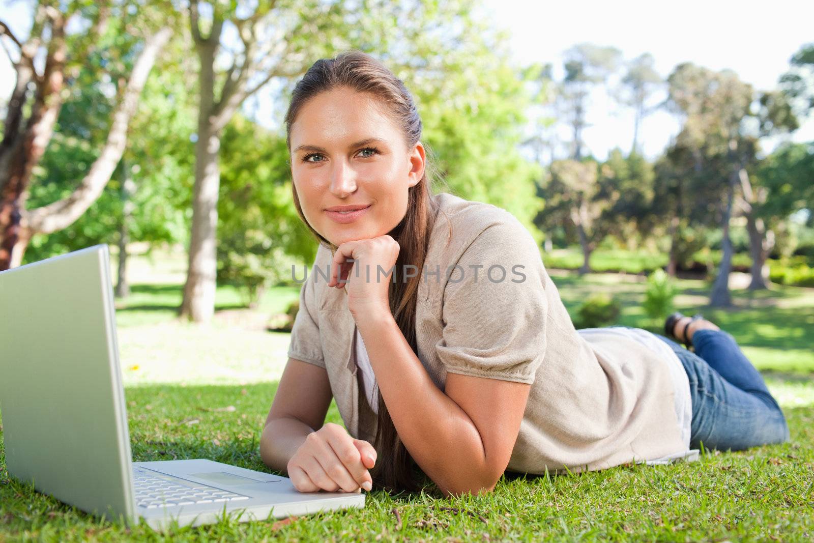 Young woman lying on the lawn with her notebook