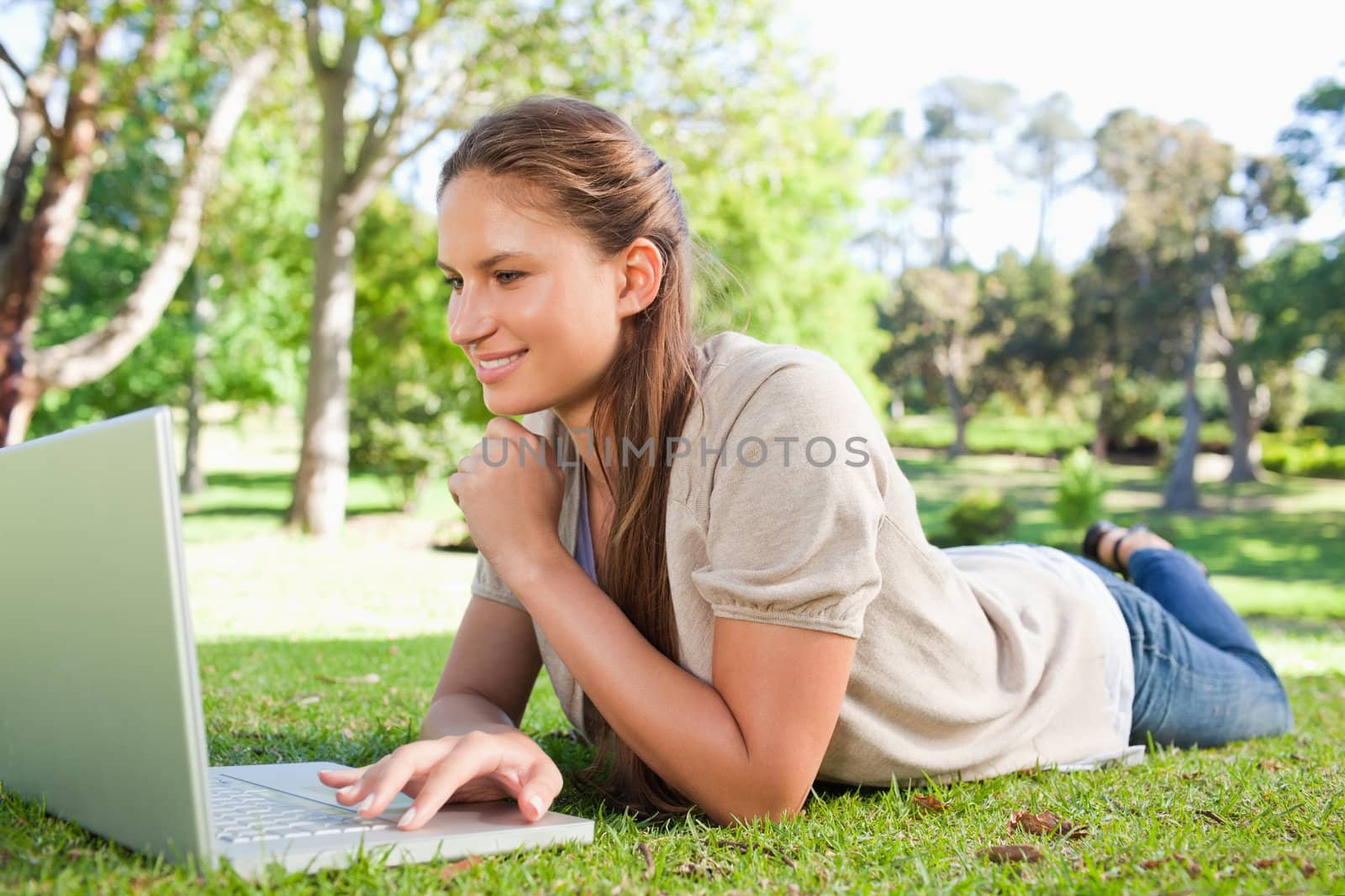 Smiling woman lying on the lawn with her notebook by Wavebreakmedia