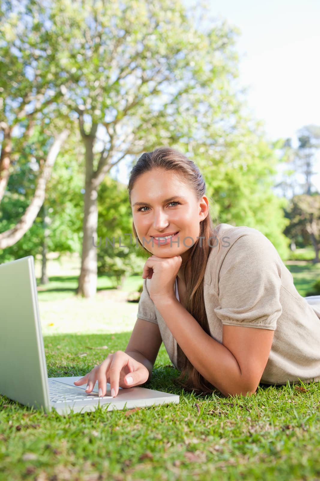 Smiling woman with her laptop while lying on the lawn by Wavebreakmedia