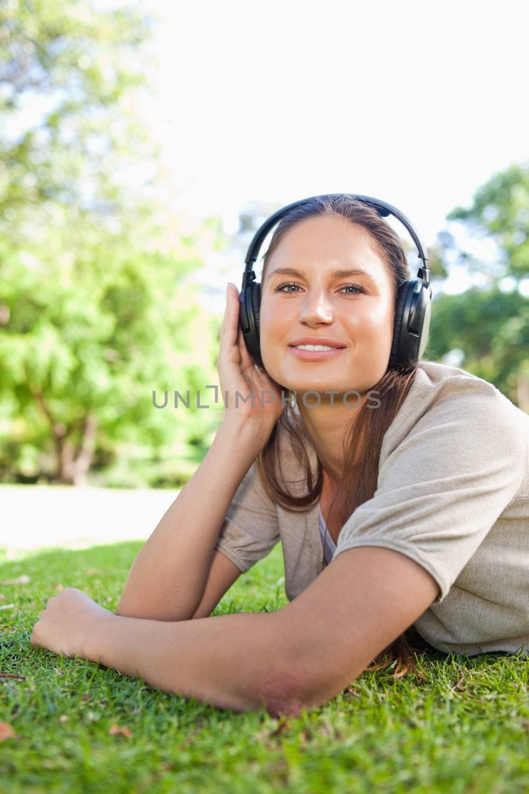 Young woman with headphones lying on the grass