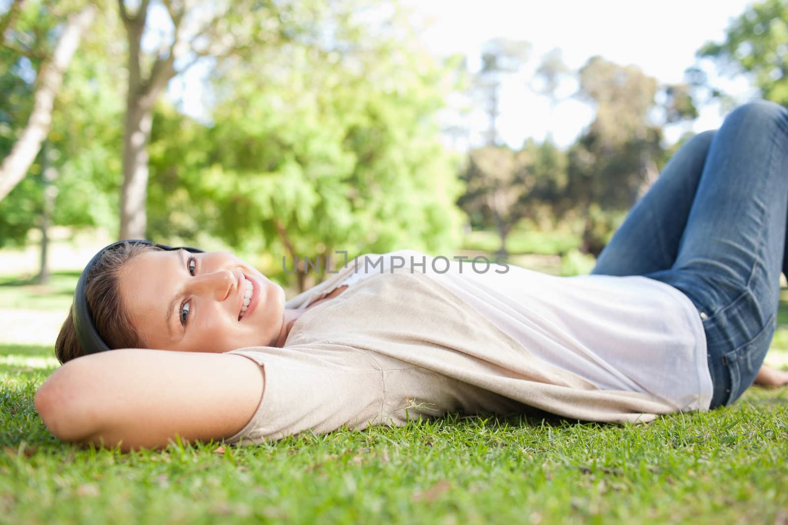 Young woman lying on the grass while listening to music