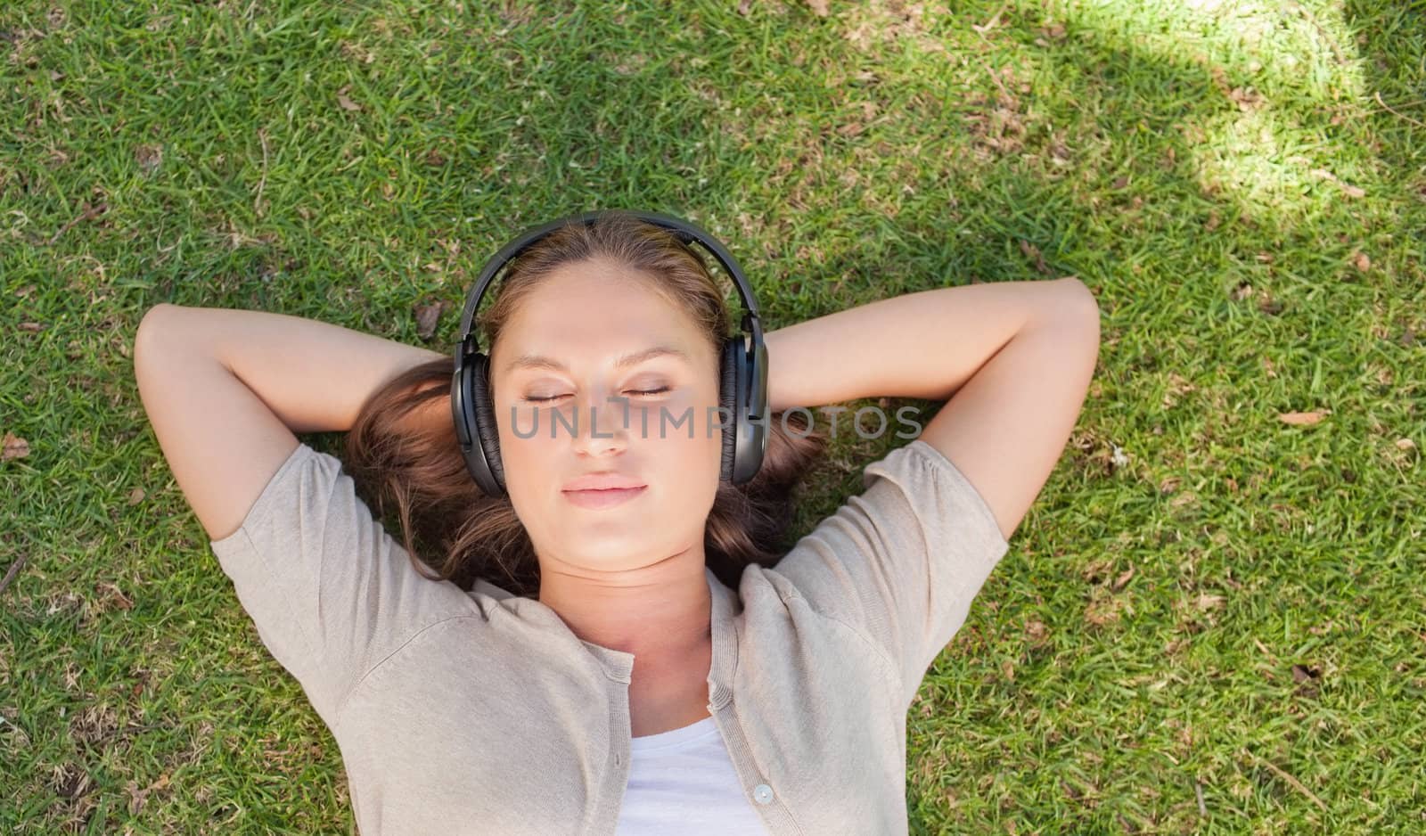 Relaxed young woman listening to music while lying on the lawn