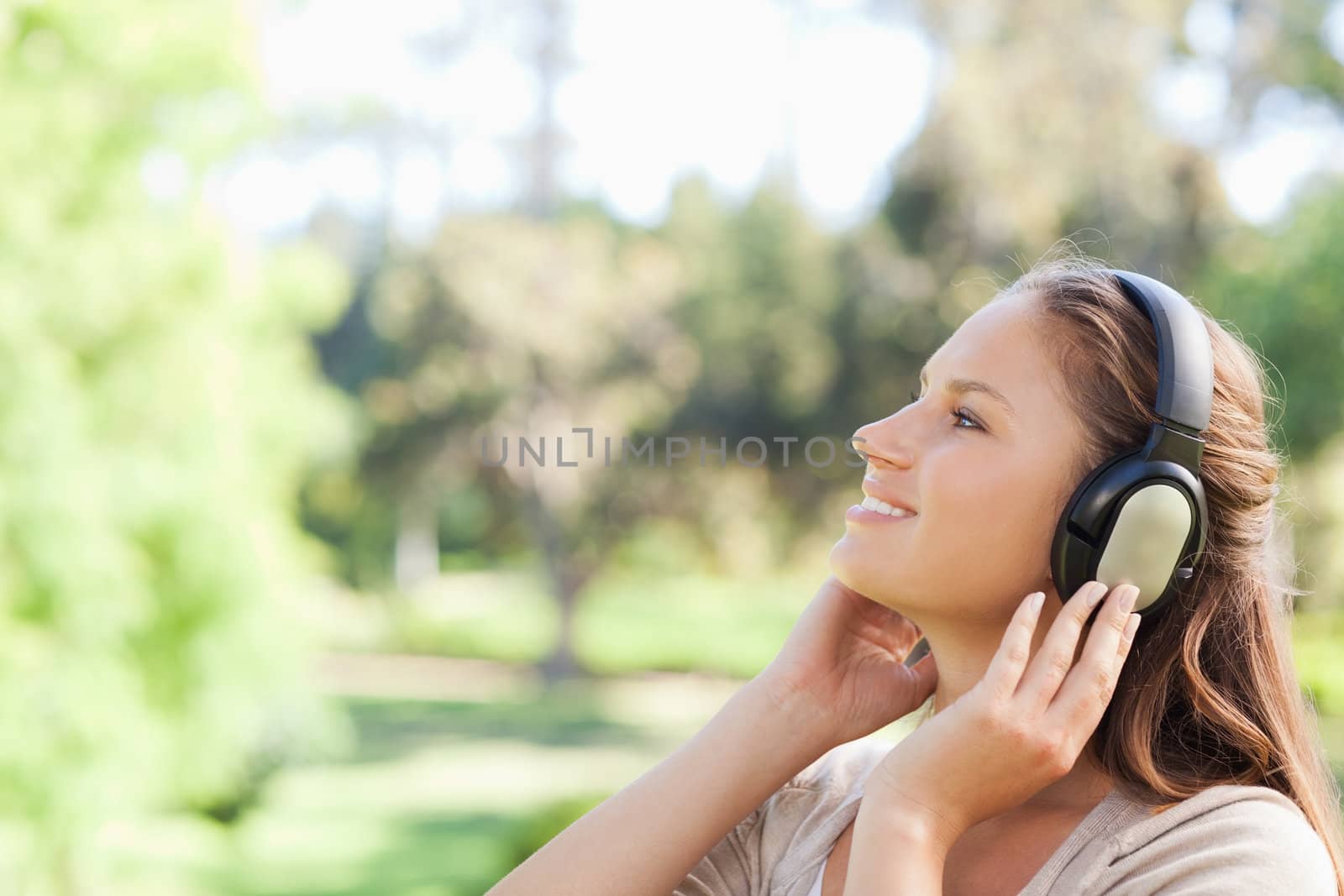 Side view of a young woman in the park enjoying music