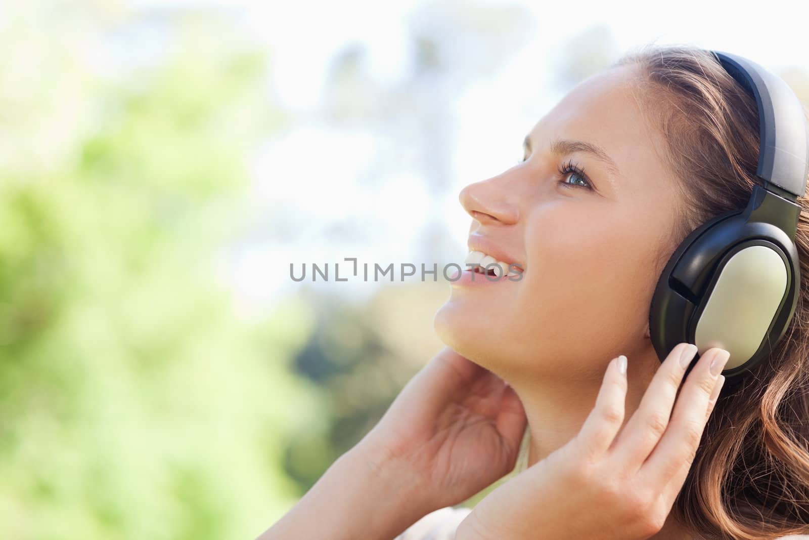 Side view of a young woman in the park listening to music