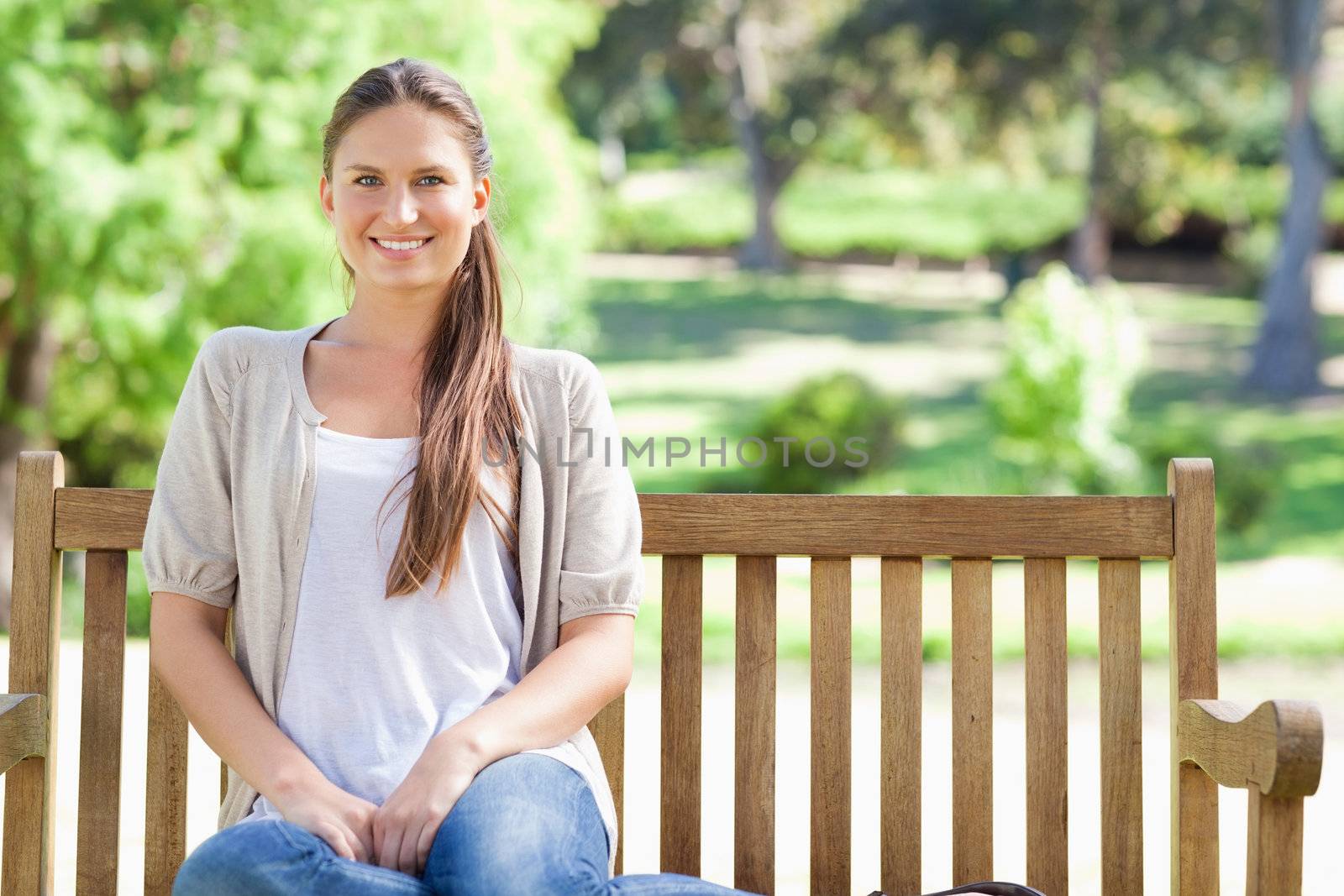 Smiling woman relaxing in the park on a bench by Wavebreakmedia