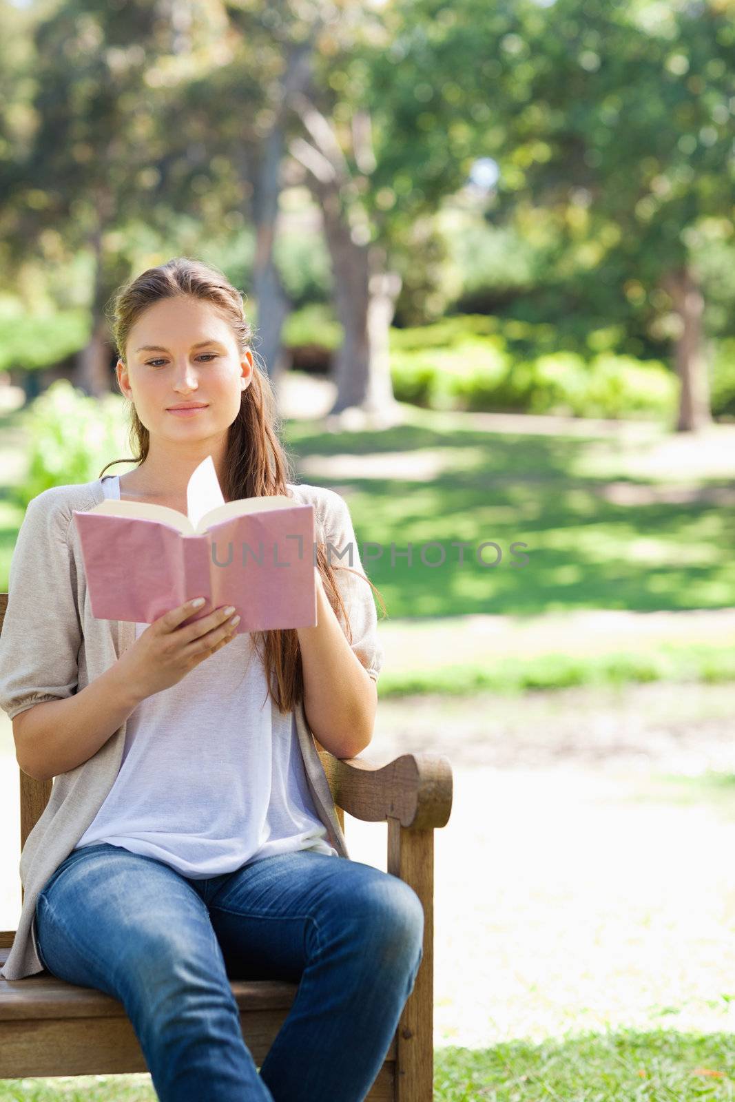 Woman reading a book on a park bench by Wavebreakmedia