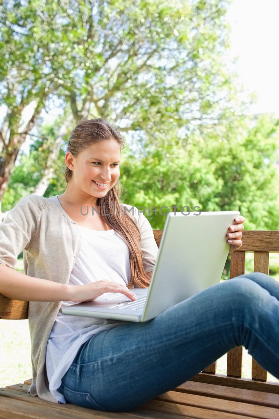 Smiling young woman with her laptop sitting on a bench