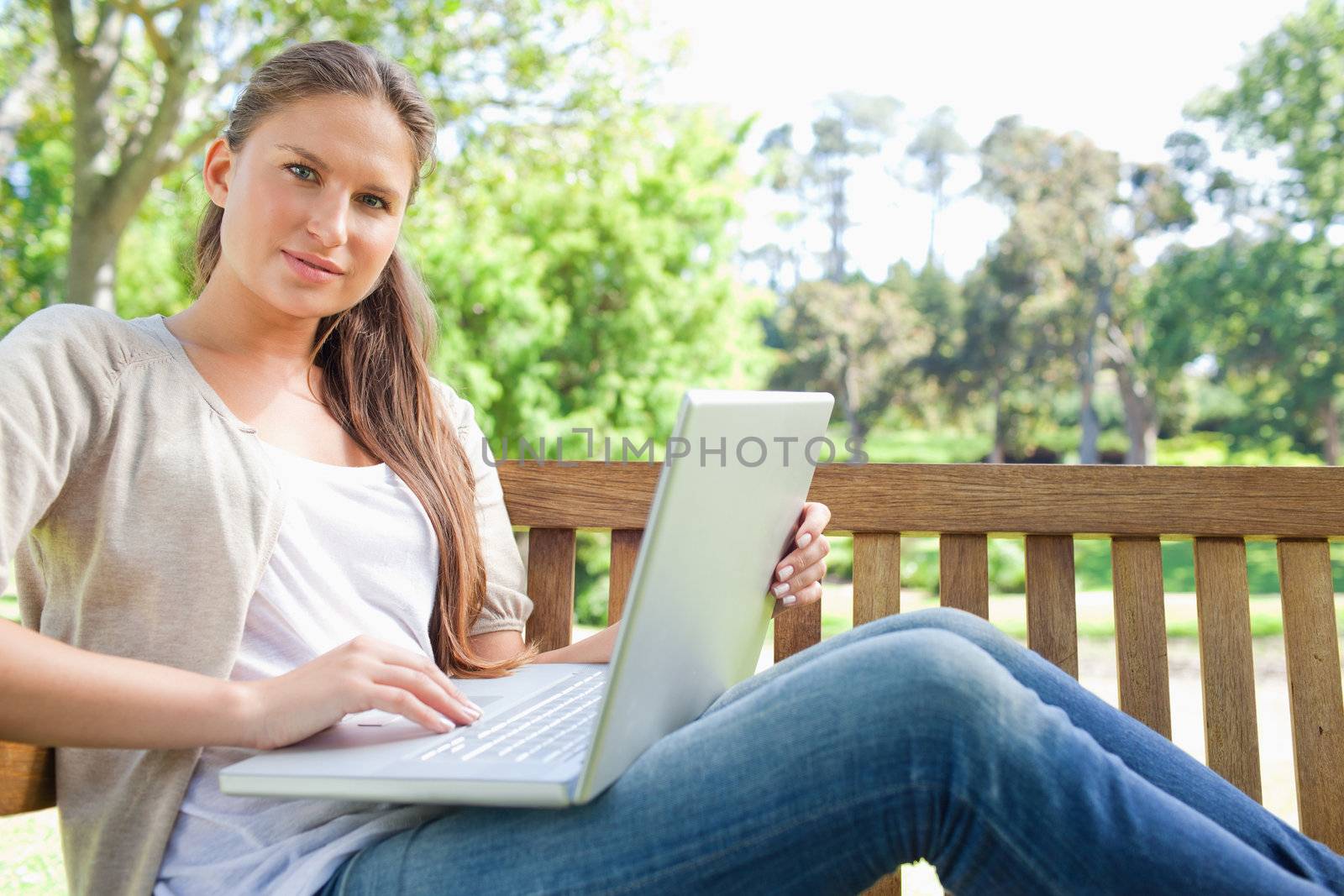 Woman with a laptop sitting on a park bench by Wavebreakmedia