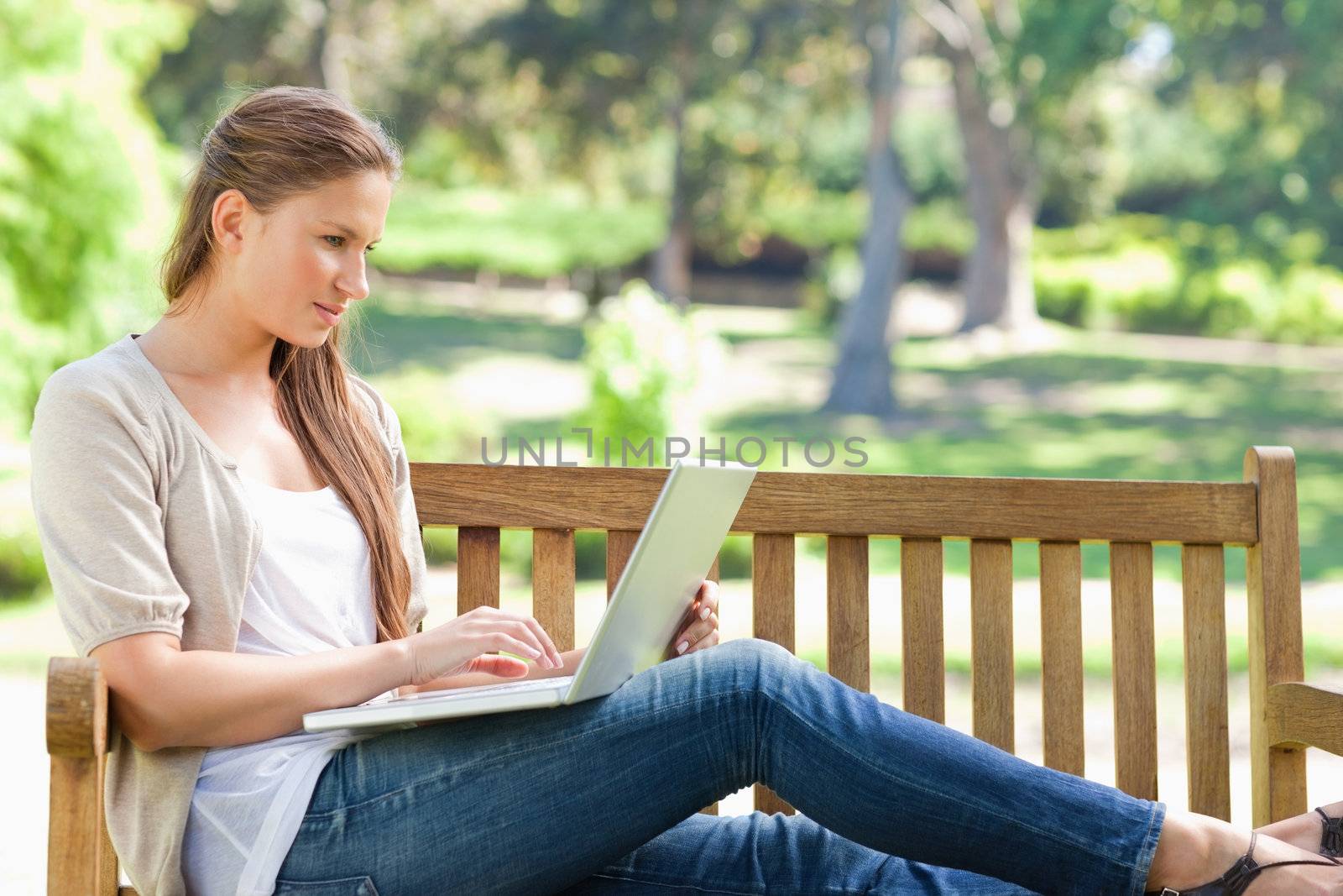 Young woman on a park bench working on her laptop