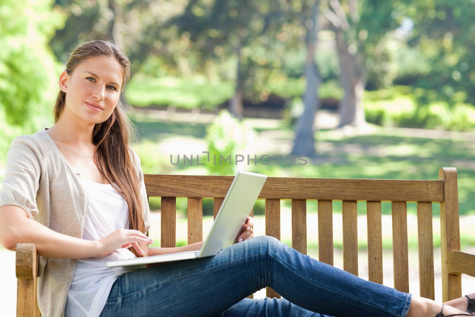 Young woman with her laptop on a park bench