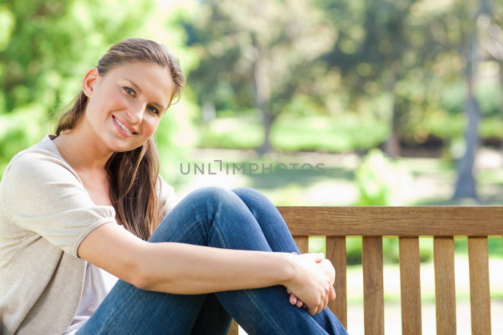 Smiling woman sitting on a park bench by Wavebreakmedia