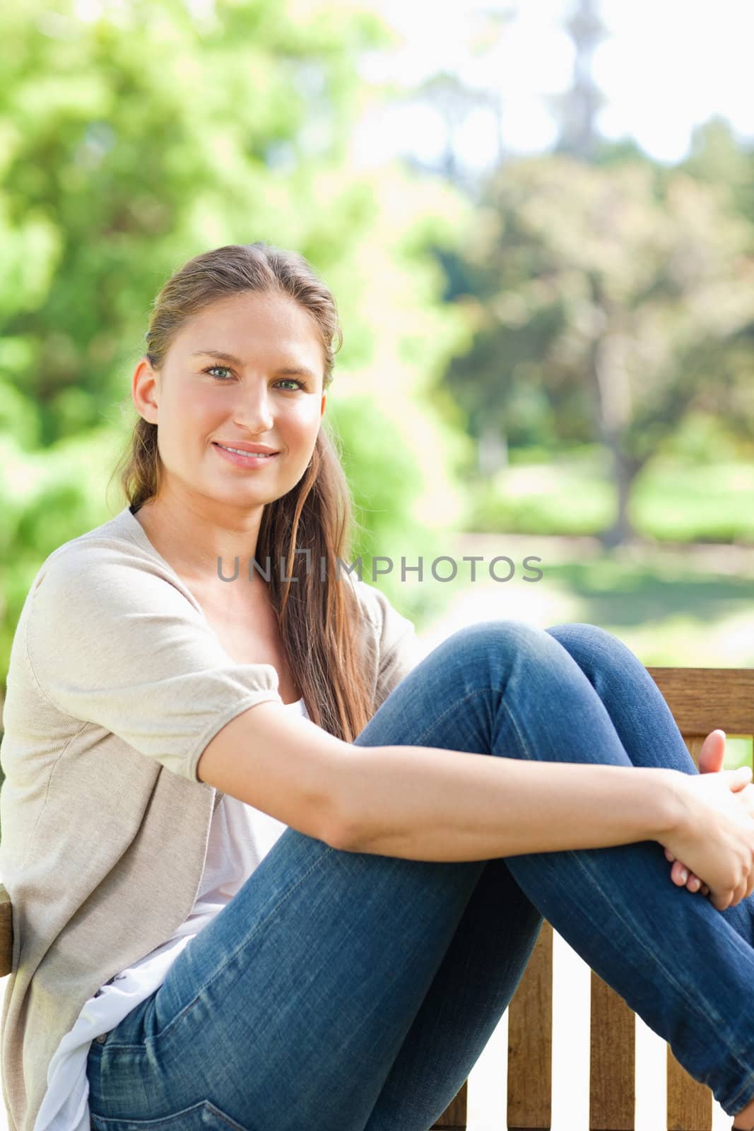 Smiling woman enjoying the sun on a park bench by Wavebreakmedia