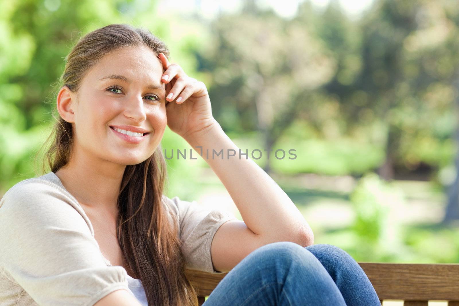 Smiling woman on a bench in the park by Wavebreakmedia