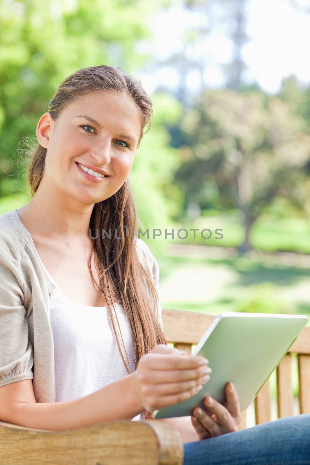 Smiling woman with her tablet on a park bench by Wavebreakmedia