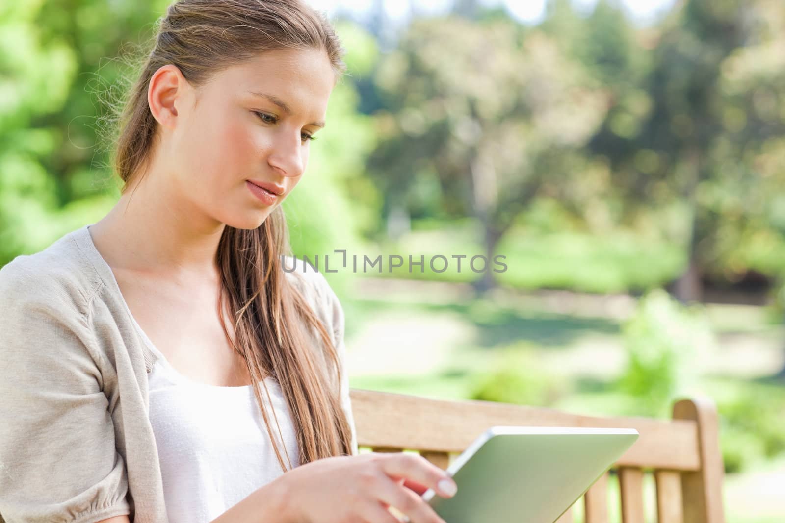 Young woman with her tablet computer sitting on a park bench