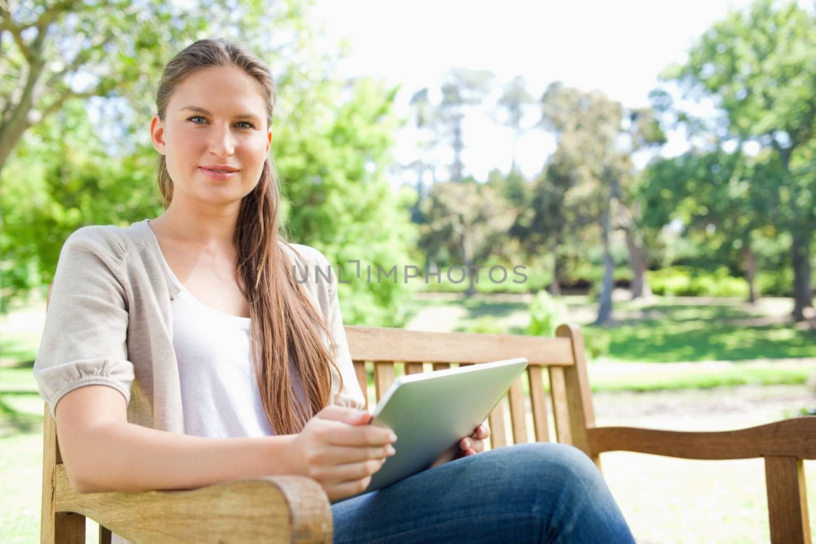 Young woman sitting on a park bench with her tablet computer