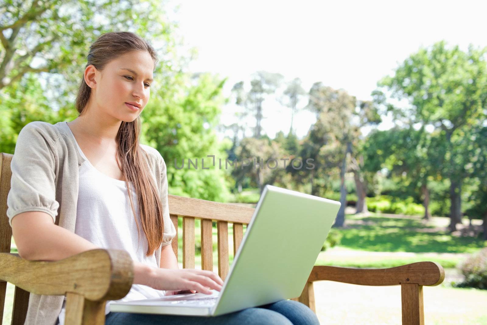 Woman with a laptop on a park bench by Wavebreakmedia