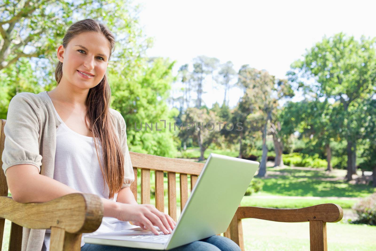 Smiling woman with a laptop on a park bench by Wavebreakmedia