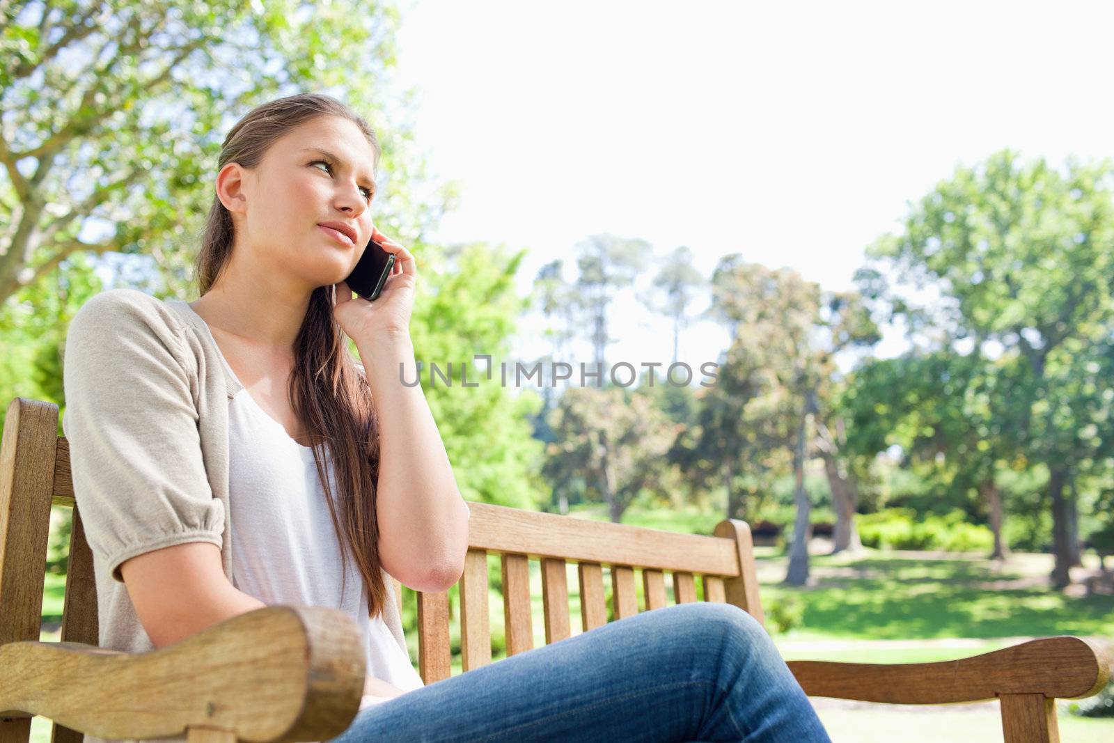 Woman talking on her phone on a park bench by Wavebreakmedia