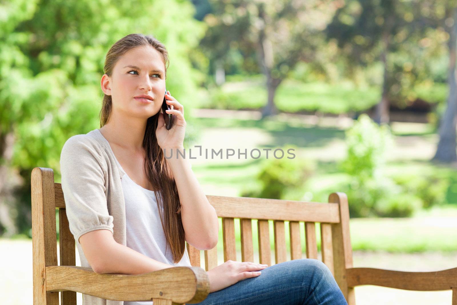Woman on her mobile phone on a park bench by Wavebreakmedia