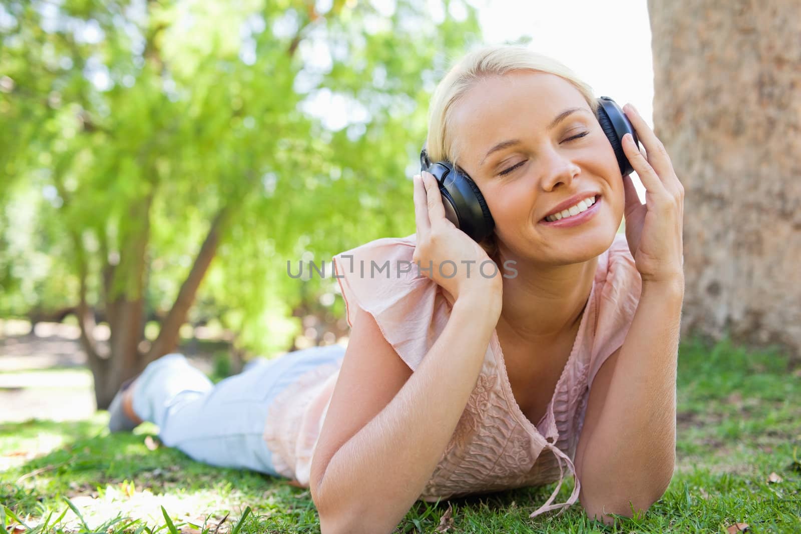 Woman wearing headphones while lying on the lawn by Wavebreakmedia