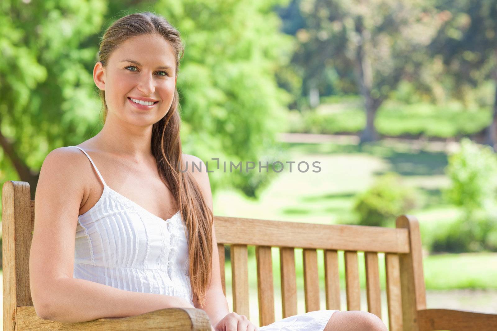 Smiling woman on a park bench by Wavebreakmedia