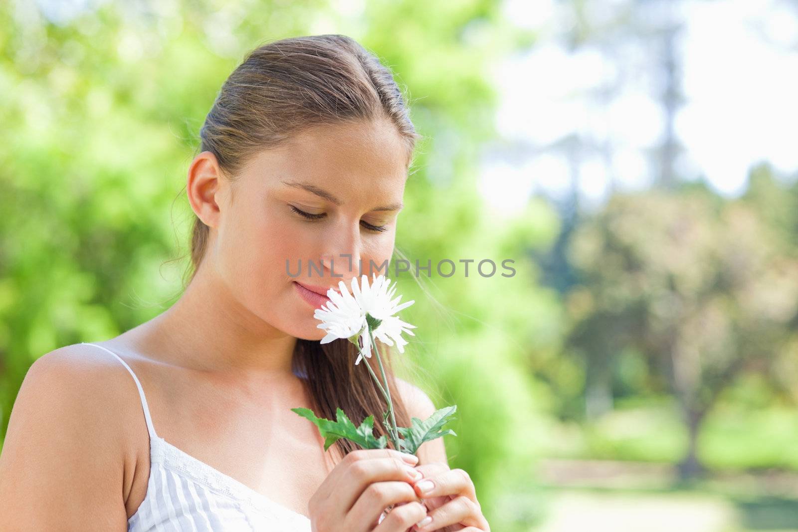 Young woman smelling on a flower in the park