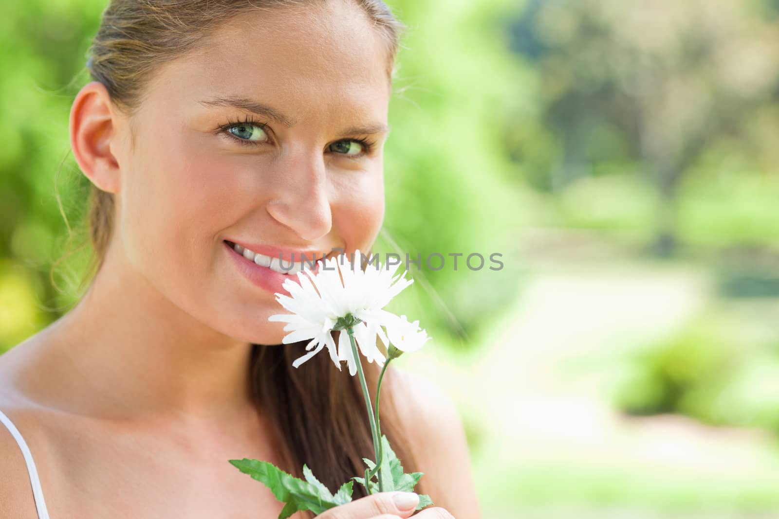 Smiling woman with a flower in the park by Wavebreakmedia