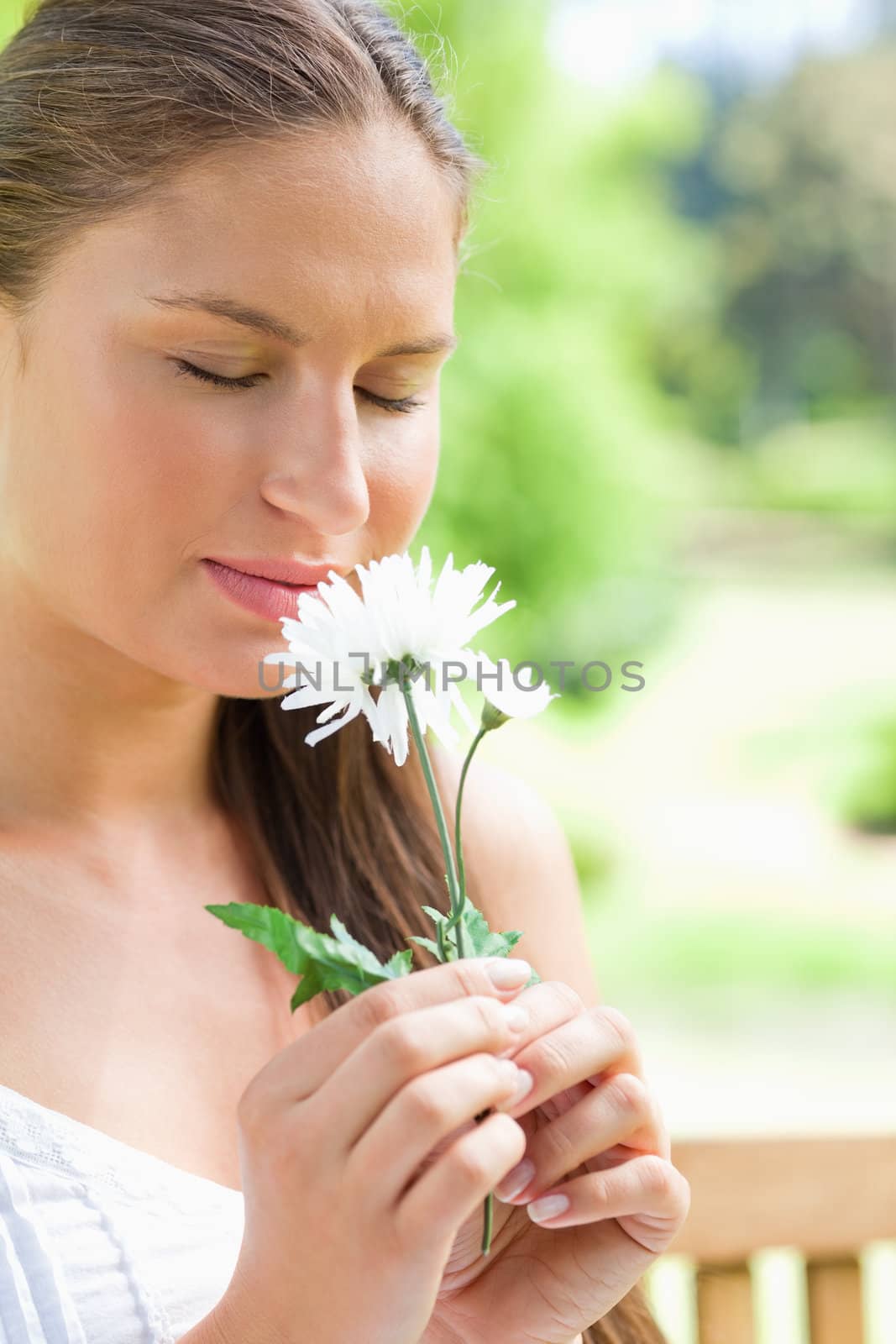 Close up of a young woman smelling a flower in the park