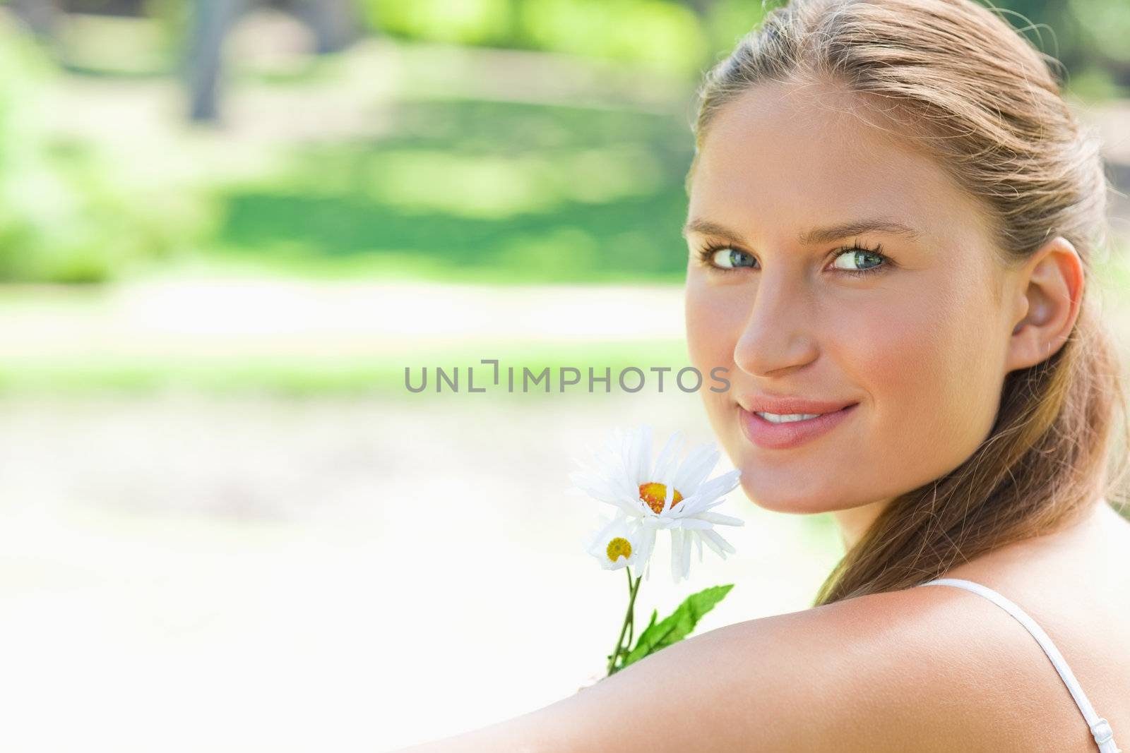 Side view of woman with a flower in the park by Wavebreakmedia