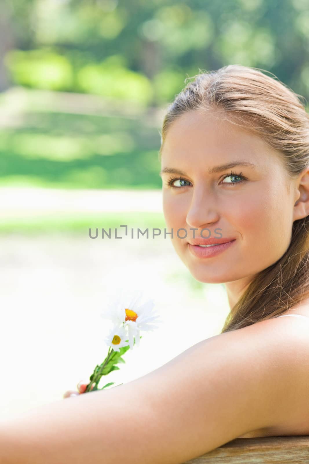 Side view of a woman holding a flower in the park by Wavebreakmedia