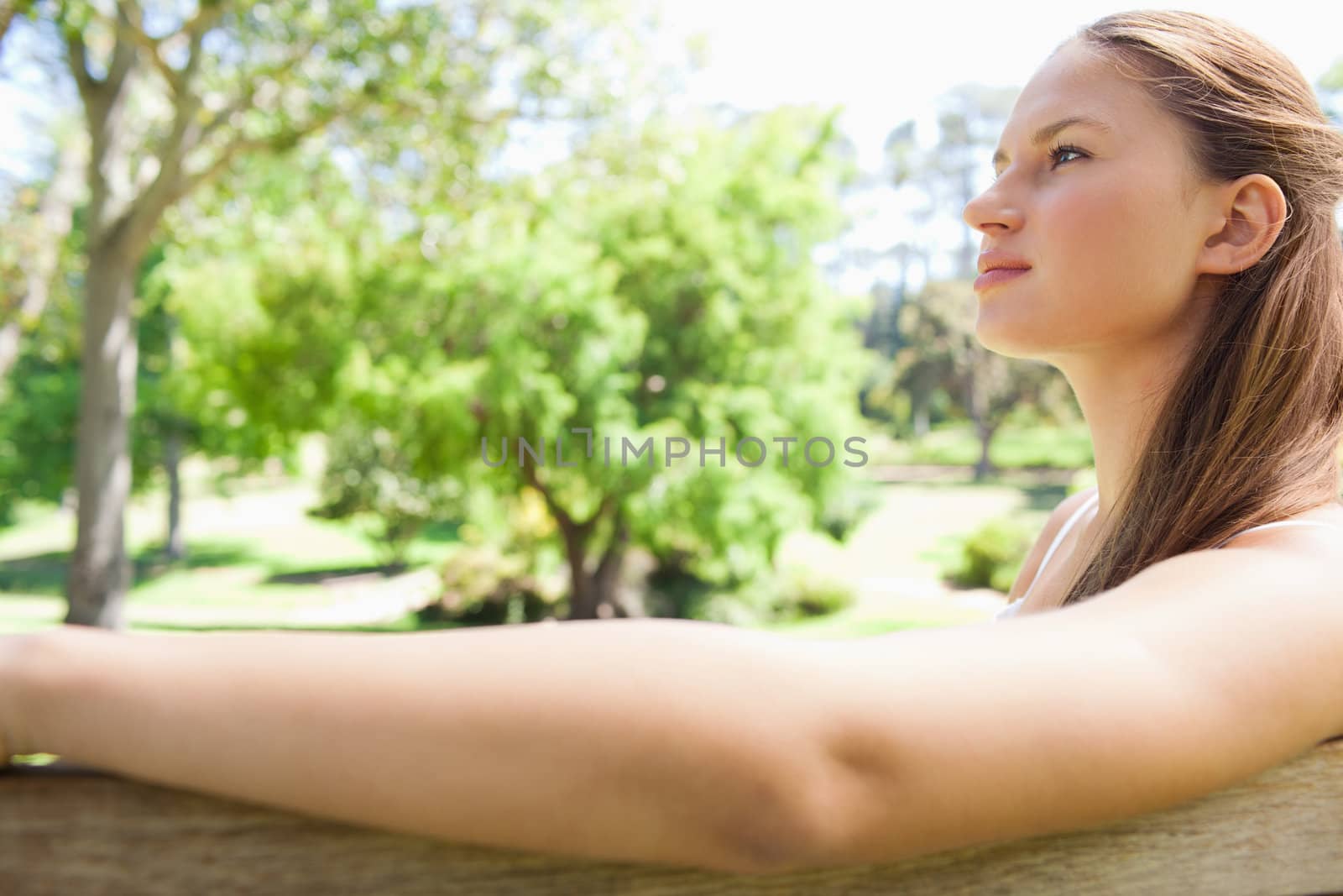 Side view of a young woman sitting on a park bench