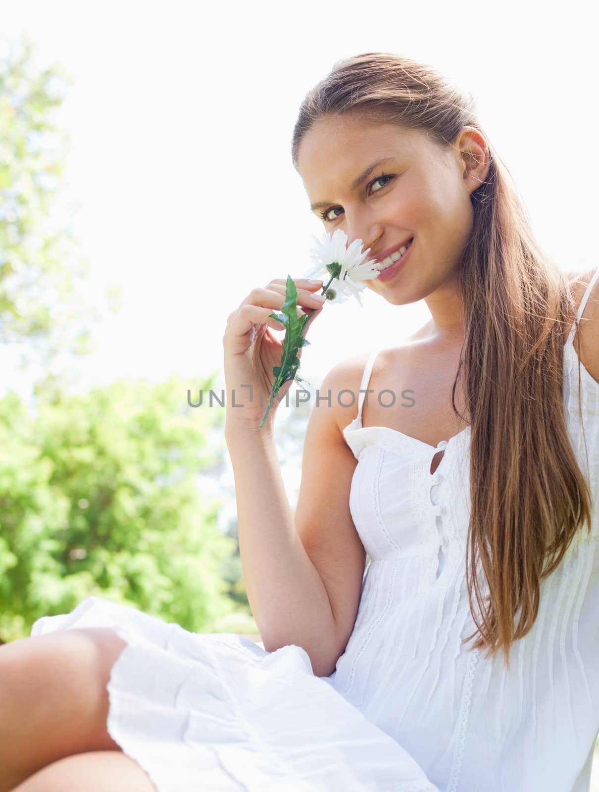 Smiling woman in the park smelling a flower by Wavebreakmedia