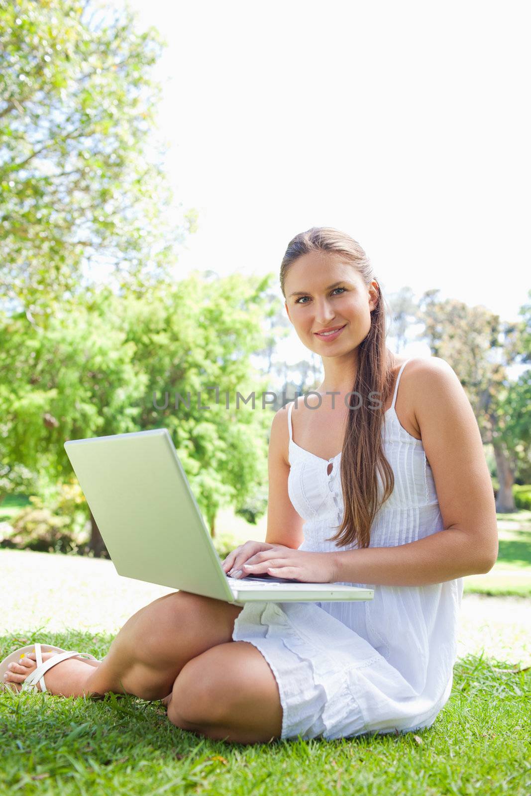 Smiling young woman on the lawn with her laptop